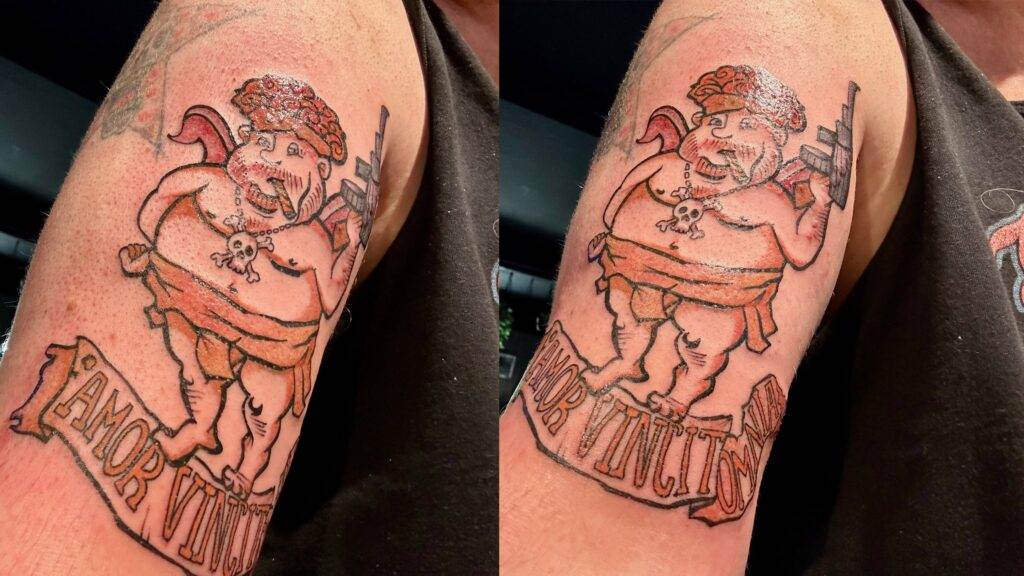 Frisch gestochenes Tattoo auf dem Oberarm: Ein Amor im Rambo-Stil mit dem Spruch „Amor Vincit Omina“